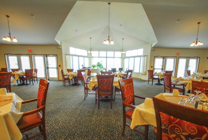 A spacious and well-lit dining room with neatly arranged tables and chairs.