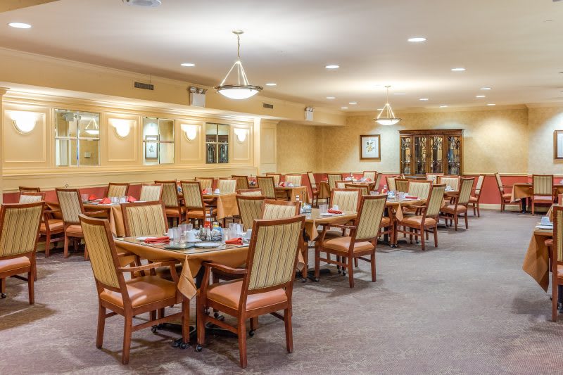 A nicely arranged dining area with multiple tables and chairs, well-lit by overhead lights.