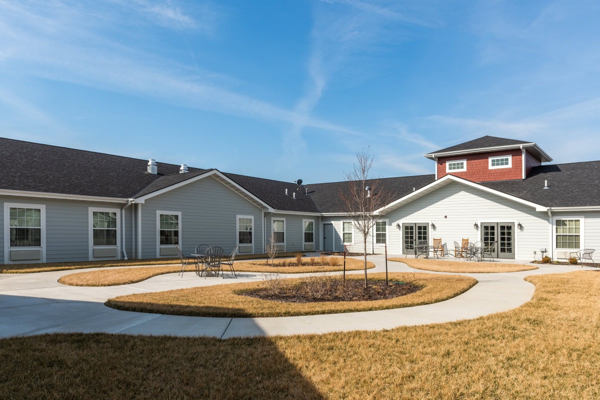 A residential building with a circular pathway and lawn under a clear blue sky.