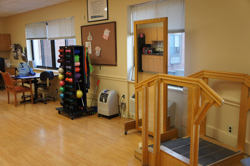 A well-equipped therapy room featuring a wooden ramp, exercise balls, and various fitness equipment.