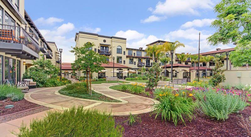 A modern building surrounded by landscaped gardens and pathways.