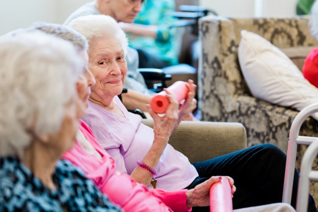 A group of elderly women participating in a fitness class, using foam rollers for exercise.