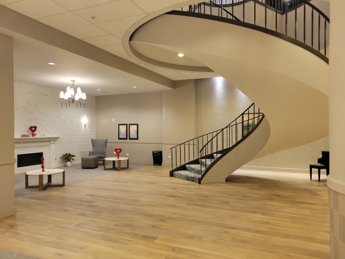 A modern lobby with a curved staircase and wooden flooring.