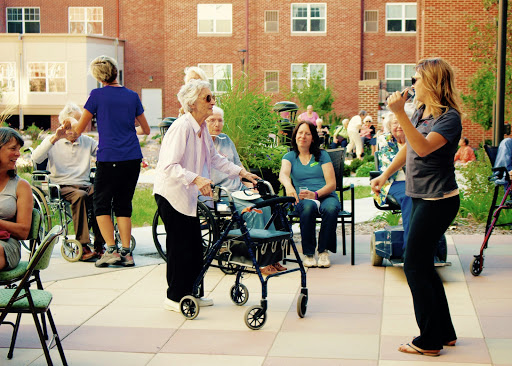 Elderly individuals enjoying a community event outdoors, with one person using a walker.