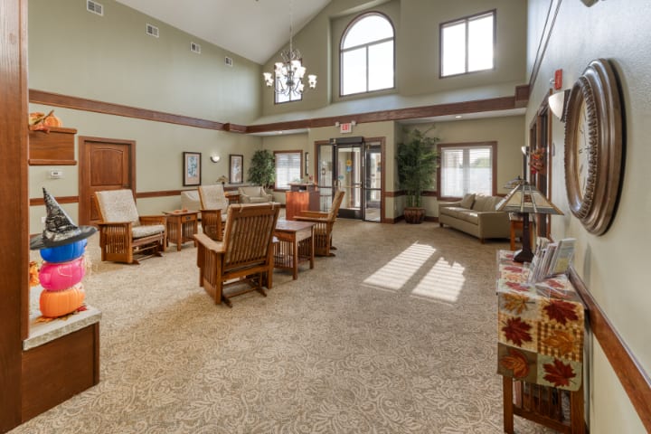 A spacious living room with high ceilings, decorated with comfortable furniture and natural lighting from large windows.