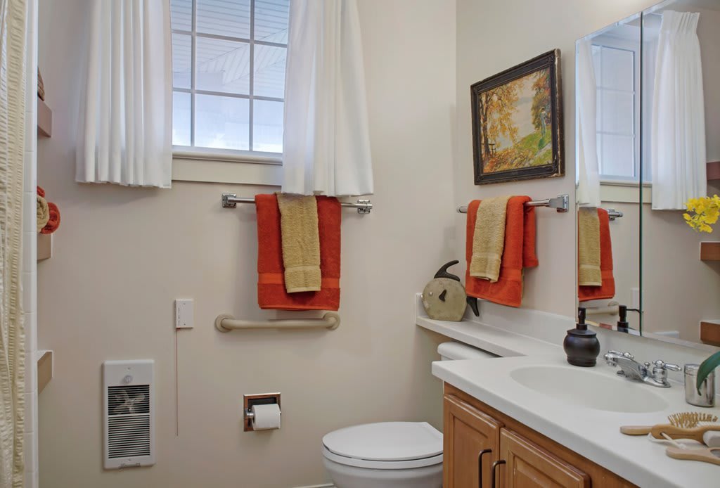 A modern bathroom with colorful towels and wall decor.