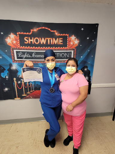 A nurse proudly displays her achievement alongside a supporter at a celebration event.
