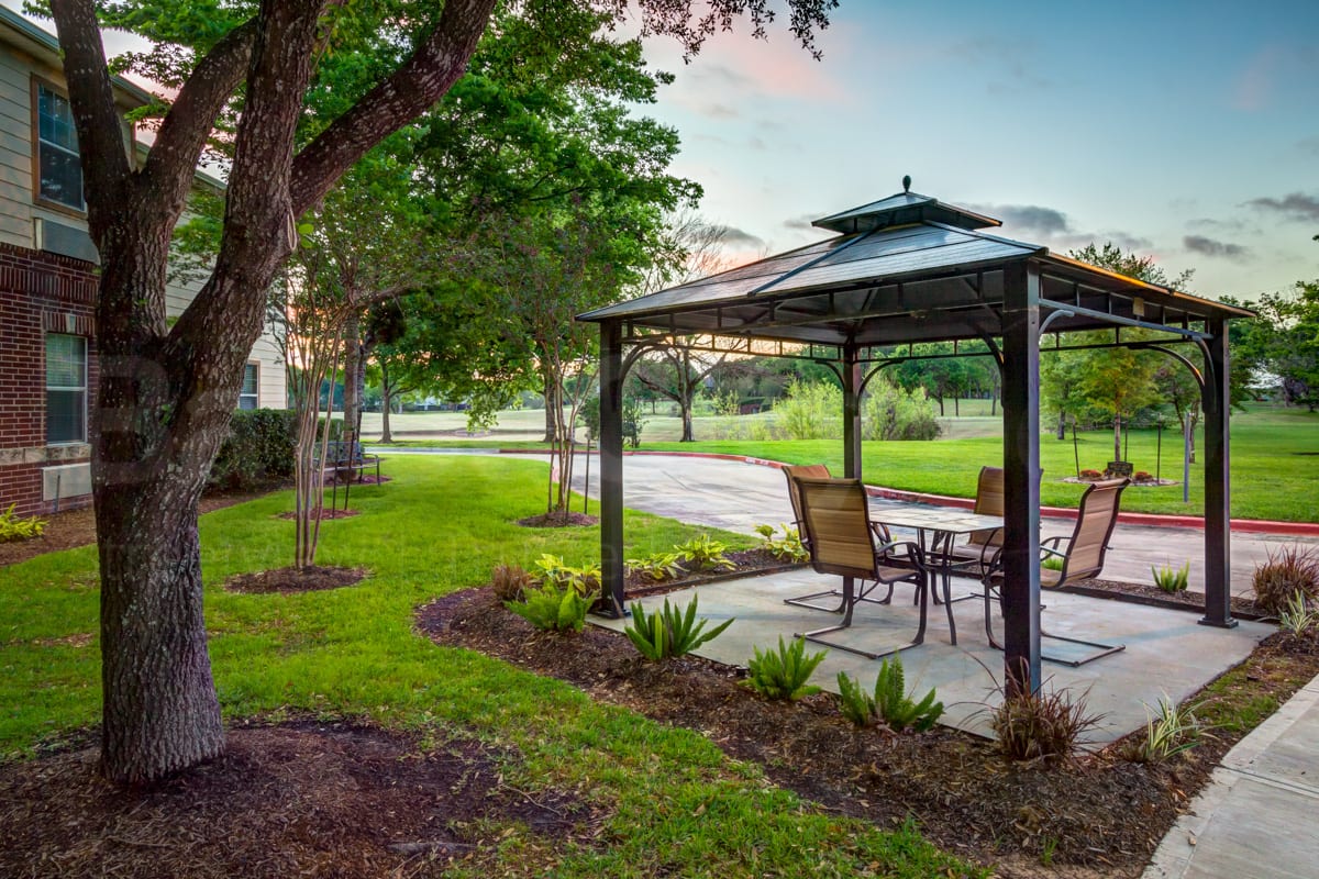 A serene outdoor patio area with a gazebo surrounded by lush greenery.
