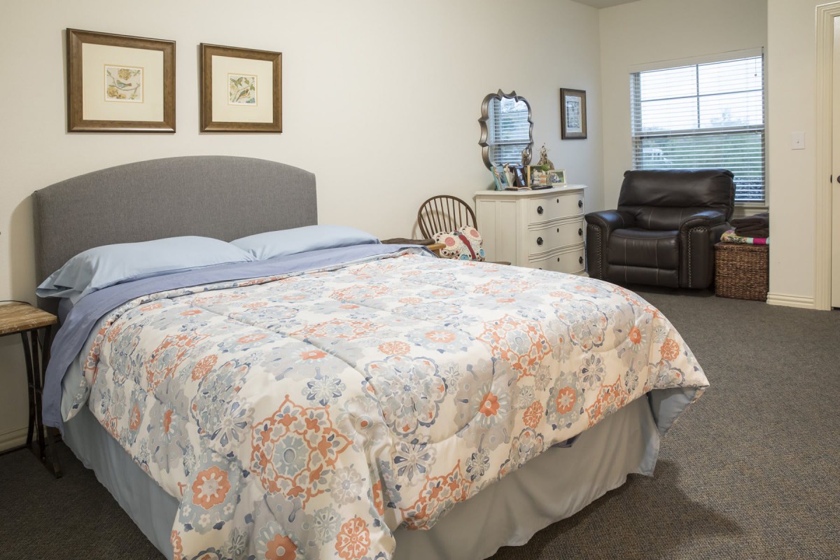 A cozy bedroom with a neatly made bed, decorative pillows, and furniture creating a welcoming atmosphere.