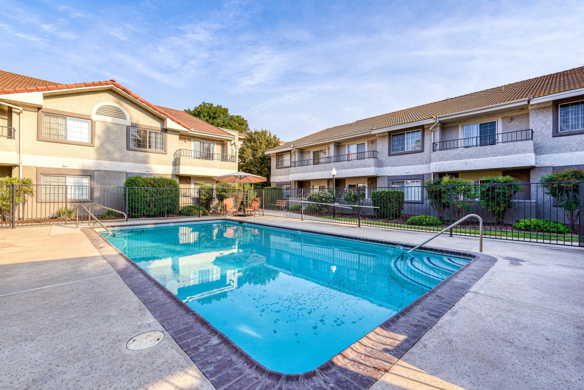 A sunny day at an apartment complex with a clean outdoor swimming pool.