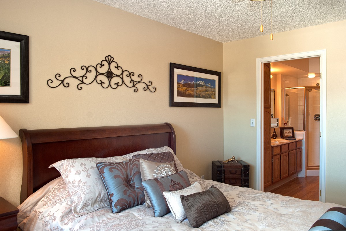 A cozy bedroom with decorative pillows and a wall hanging.