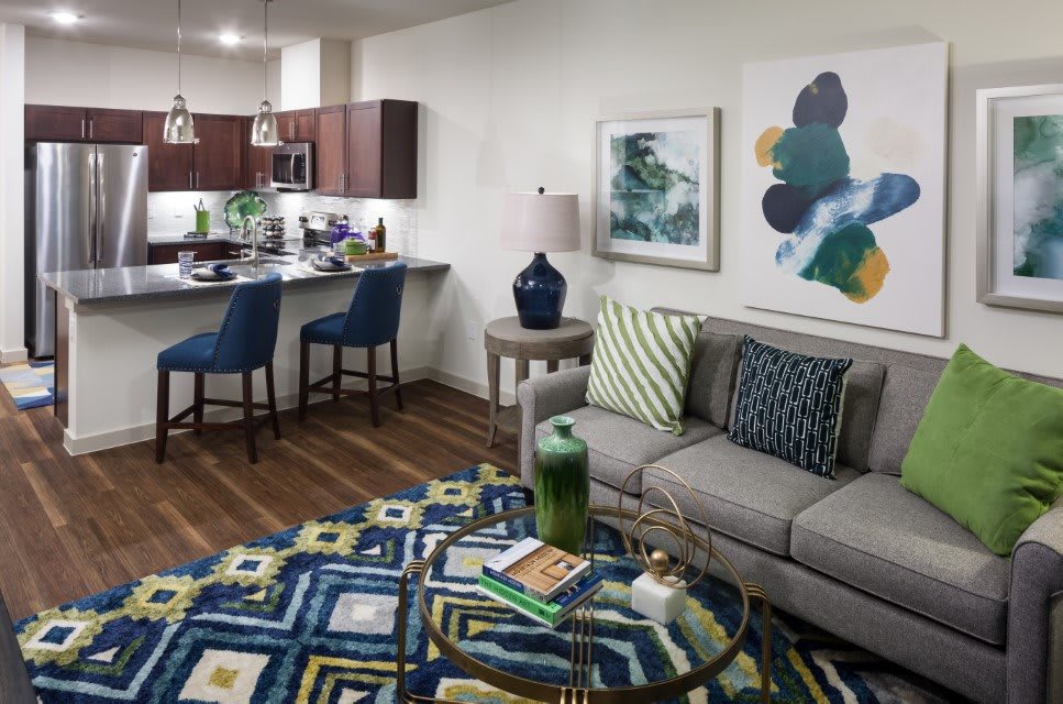 A modern open-concept living room and kitchen area featuring stylish furniture and vibrant artwork.