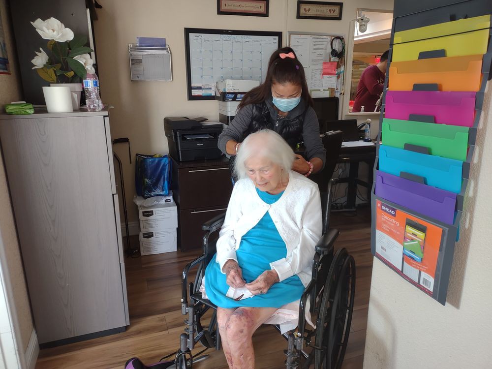 A caregiver assists an elderly woman in a wheelchair inside a nursing home.