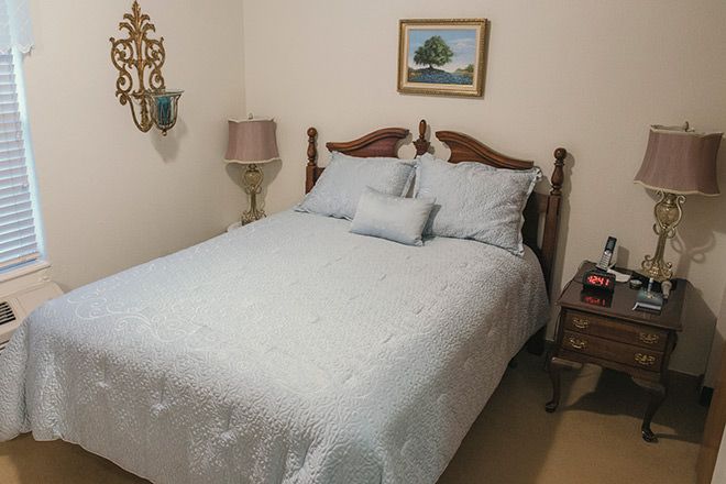 A cozy bedroom with a neatly made bed, decorative pillows, and elegant furnishings.