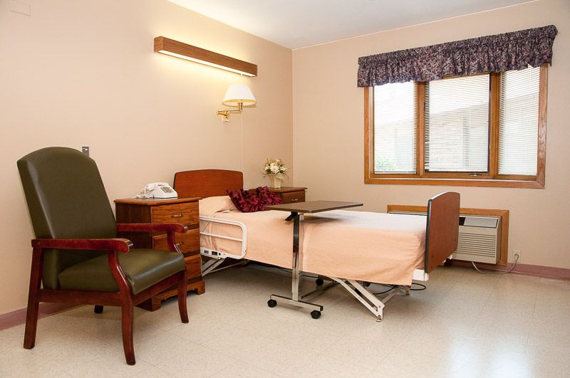 A hospital room with a bed and chair, designed for patient care.