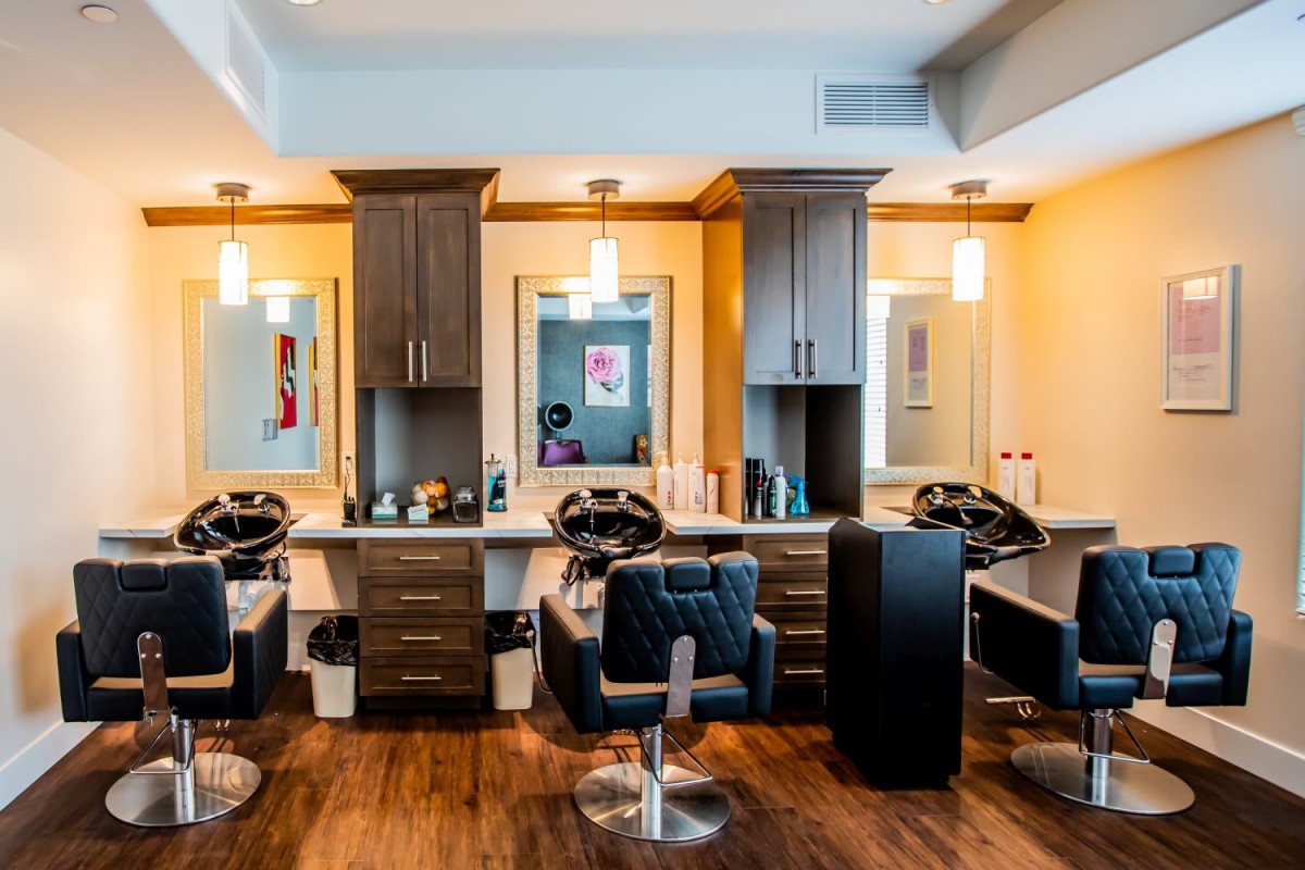 A spacious hair salon with modern chairs and mirrors, illuminated by warm lighting.