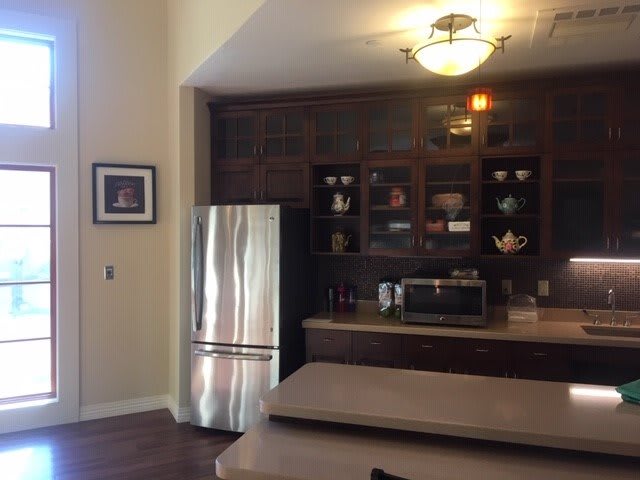 A cozy kitchen with dark wood cabinets, a stainless steel refrigerator, and a countertop with a microwave.