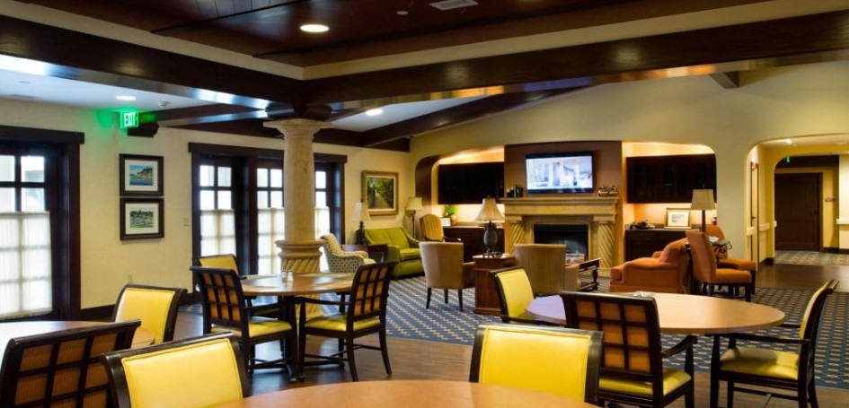 A cozy lounge area with tables and chairs, featuring a fireplace and a TV.