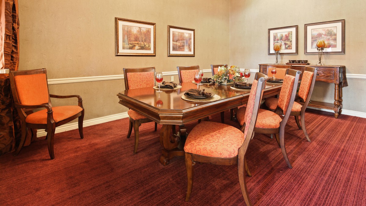 A well-decorated dining room with a large table and upholstered chairs.
