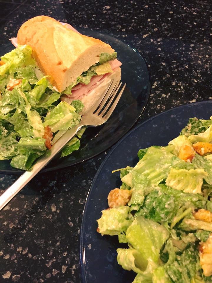 A meal featuring a sandwich and a fresh salad on dark plates.