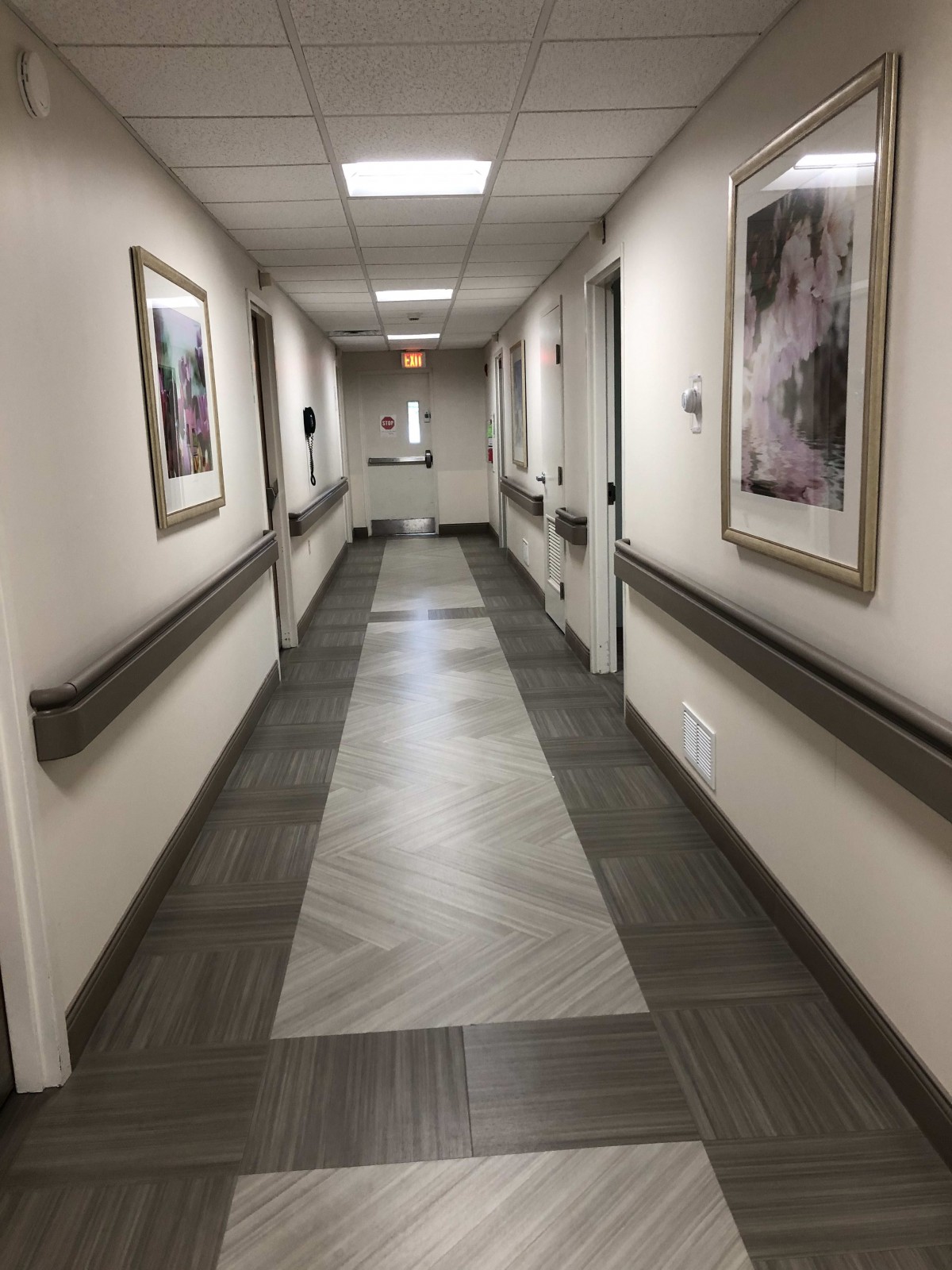 A well-lit hospital hallway with framed pictures on the walls.