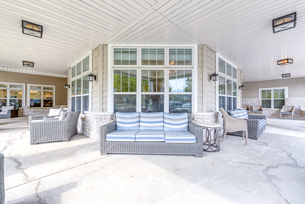 A cozy outdoor patio area with comfortable seating arrangements and large windows.