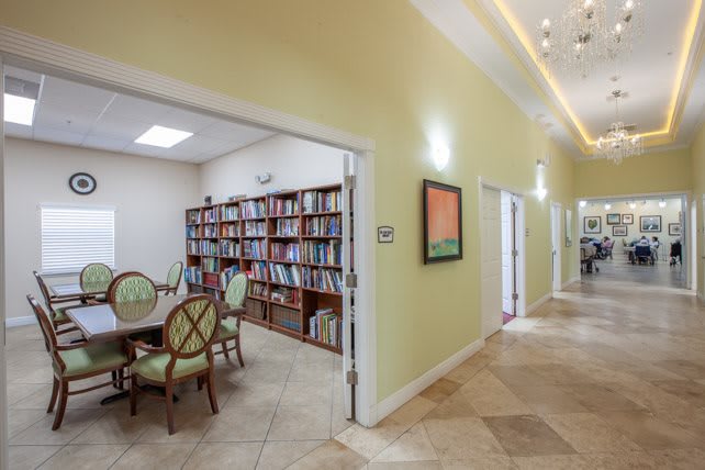 A cozy library with bookshelves, a round table, and chairs located off a hallway.
