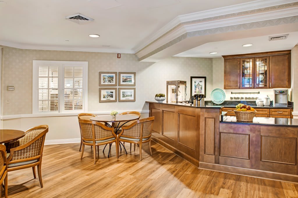 A cozy interior space featuring a wooden reception desk and chairs, with decorative artwork on the walls.