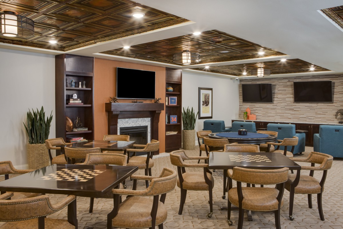 A cozy and stylish restaurant seating area with wooden tables, chairs, and a fireplace.