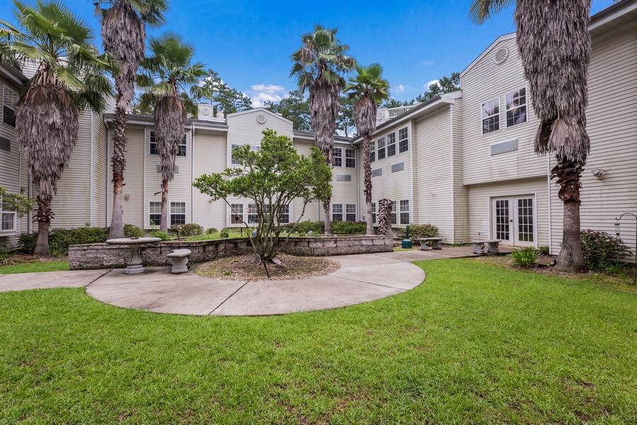 A serene courtyard with palm trees and well-maintained landscaping beside a multi-story building.