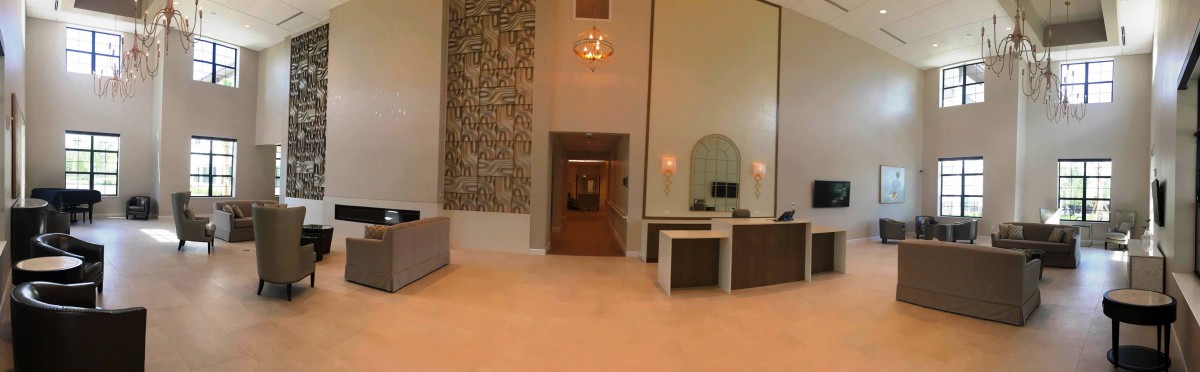 A modern lobby with a chandelier, reception desks, and decorative artwork.