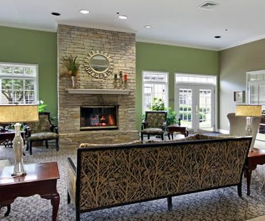 A cozy living room with a fireplace and ample seating, featuring modern decor and green walls.