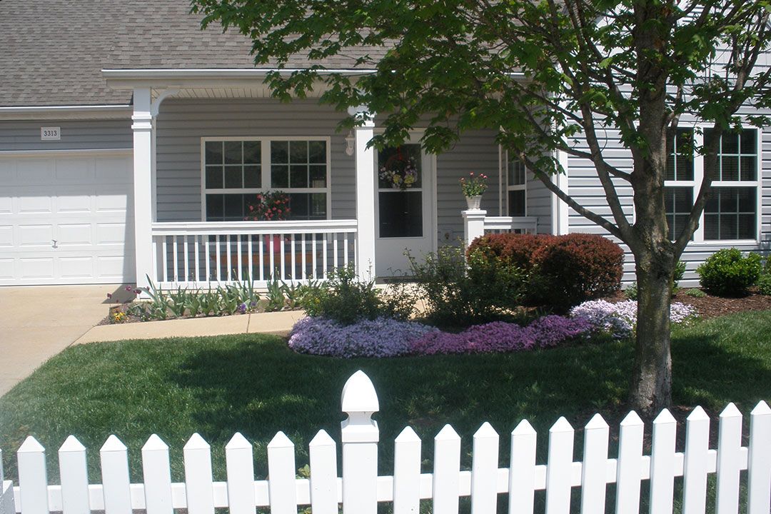 A charming single-story house with a white picket fence and a landscaped front yard.