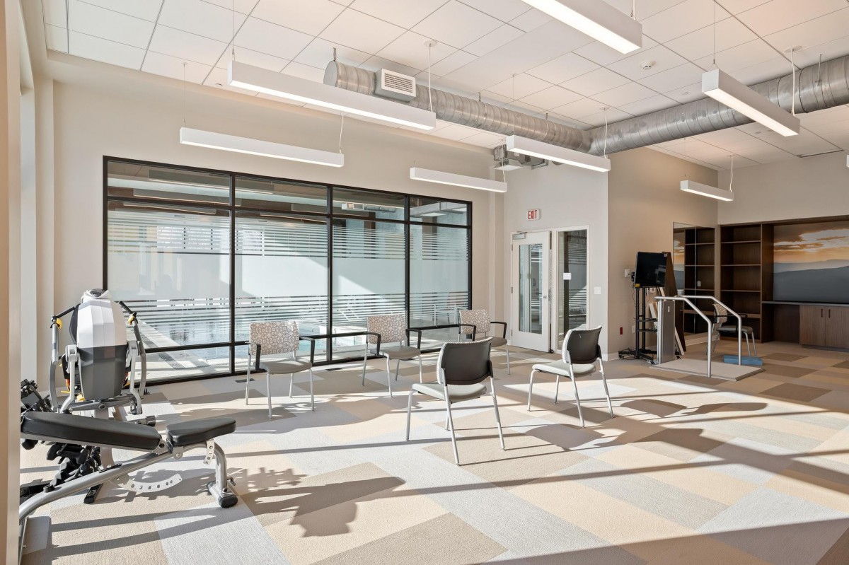 A modern office meeting area with chairs arranged in an open space, featuring glass walls and contemporary design elements.