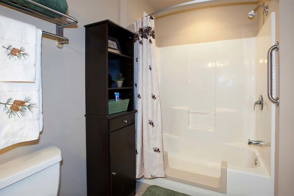 A clean and organized bathroom with a shower, curtain, cabinet, and toilet.