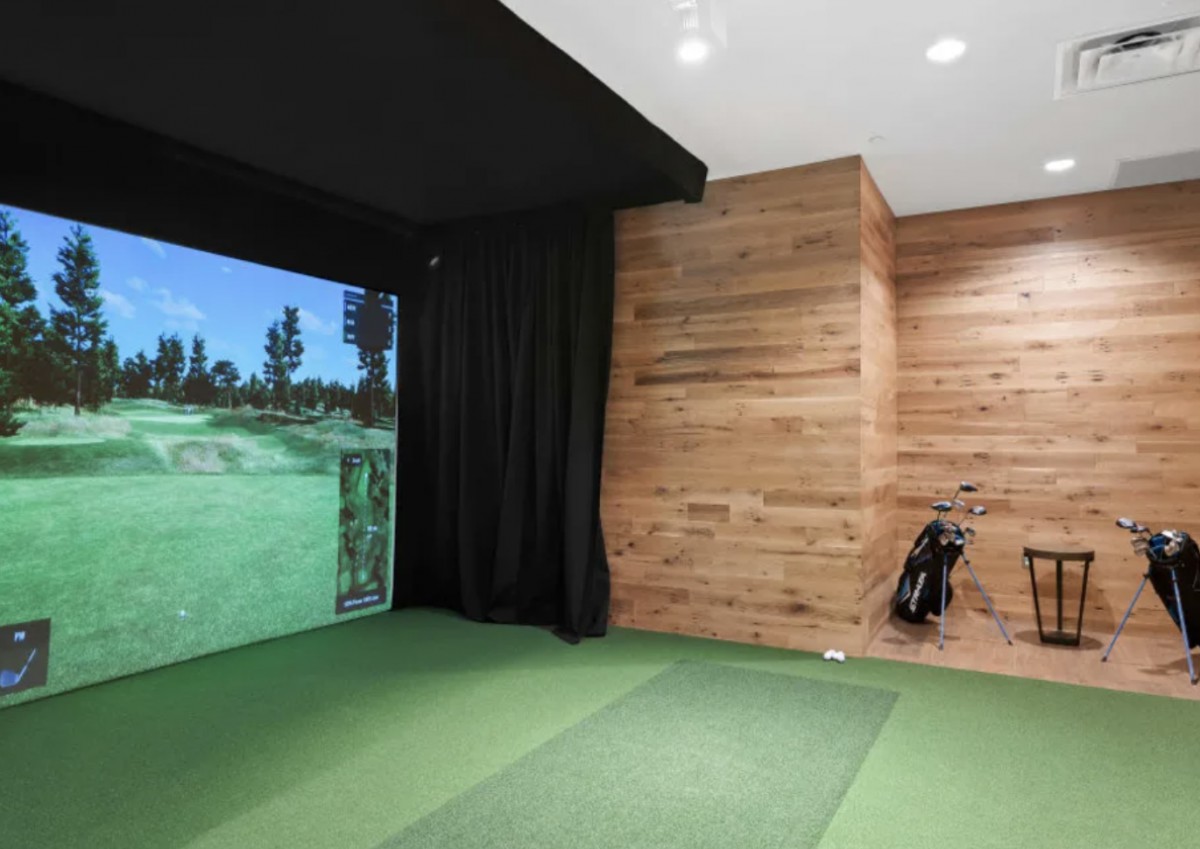 A modern indoor golf simulator with a virtual course projection and golf clubs.