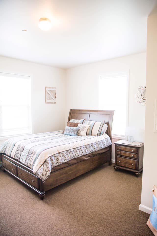 A cozy and minimalist bedroom featuring a wooden bed with patterned bedding and a matching nightstand.
