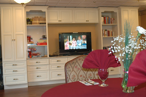 A cozy living space featuring a television, shelves filled with books, and an elegantly set dining table.