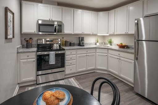 A modern kitchen featuring white cabinets and stainless steel appliances, with a cozy table set for enjoying cookies.