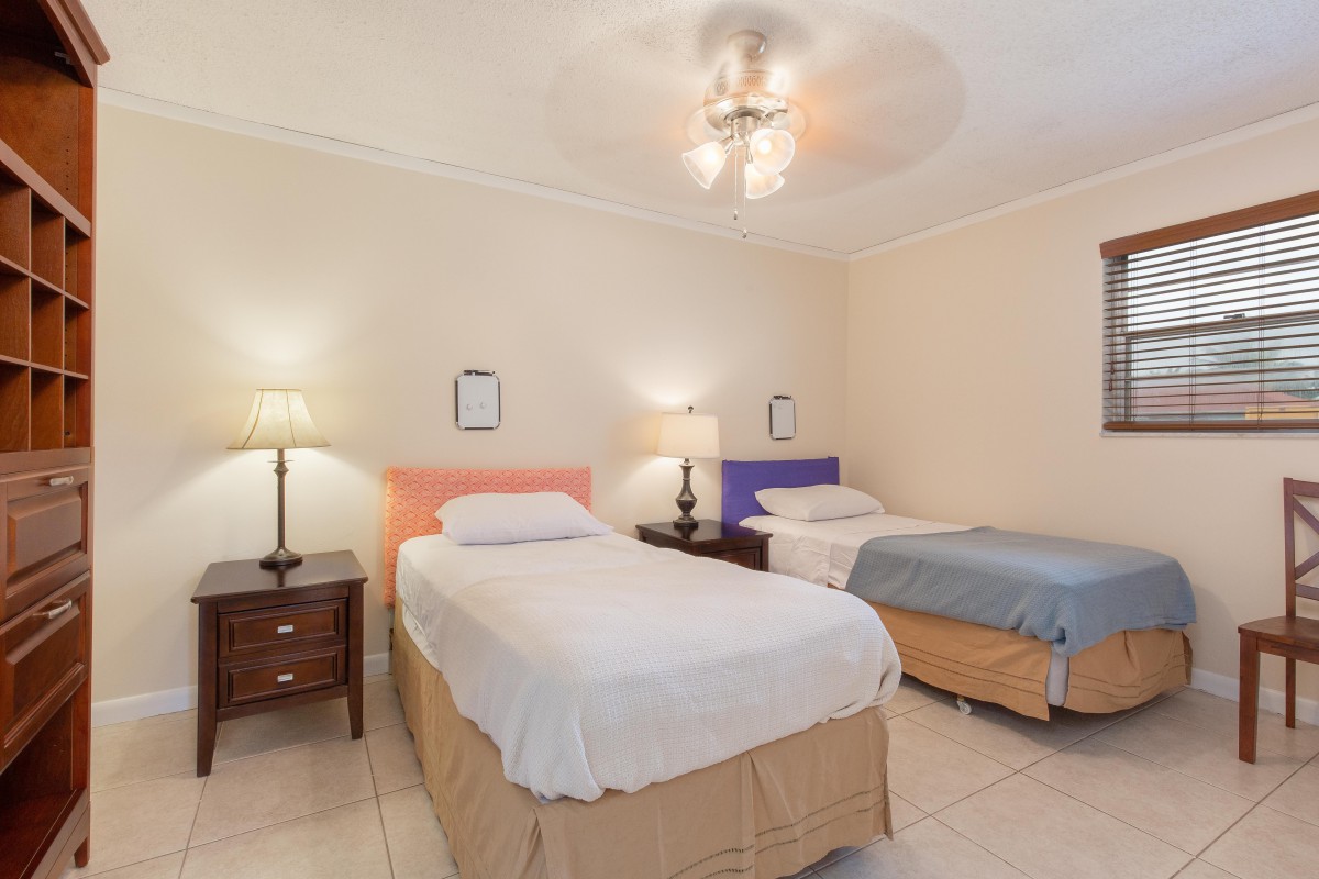 A cozy bedroom featuring two single beds with colorful headboards, illuminated by bedside lamps and a ceiling light.