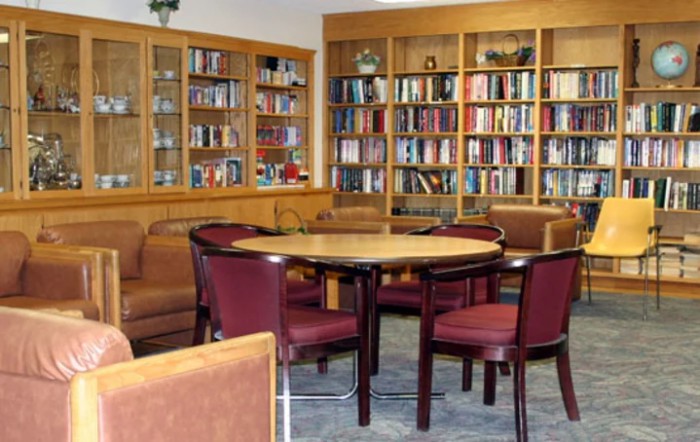 A cozy library room with bookshelves, a round table, and comfortable chairs.