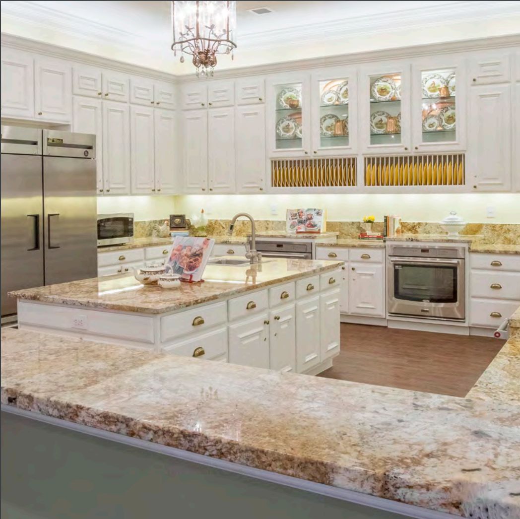 A luxurious modern kitchen with a central island, marble countertops, and stainless steel appliances.