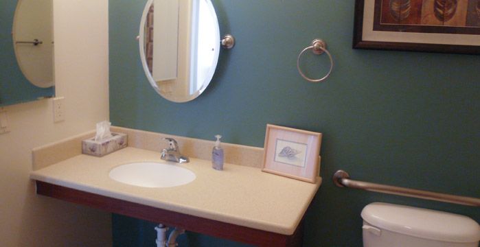 A clean bathroom with a mirror above the sink and simple decor on the countertop.