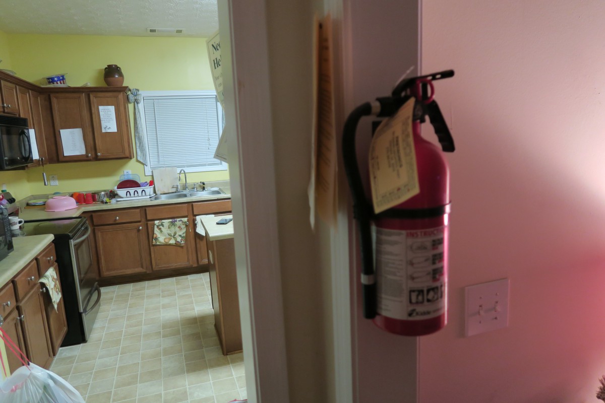 A fire extinguisher mounted on a wall near a kitchen entrance, emphasizing home safety.