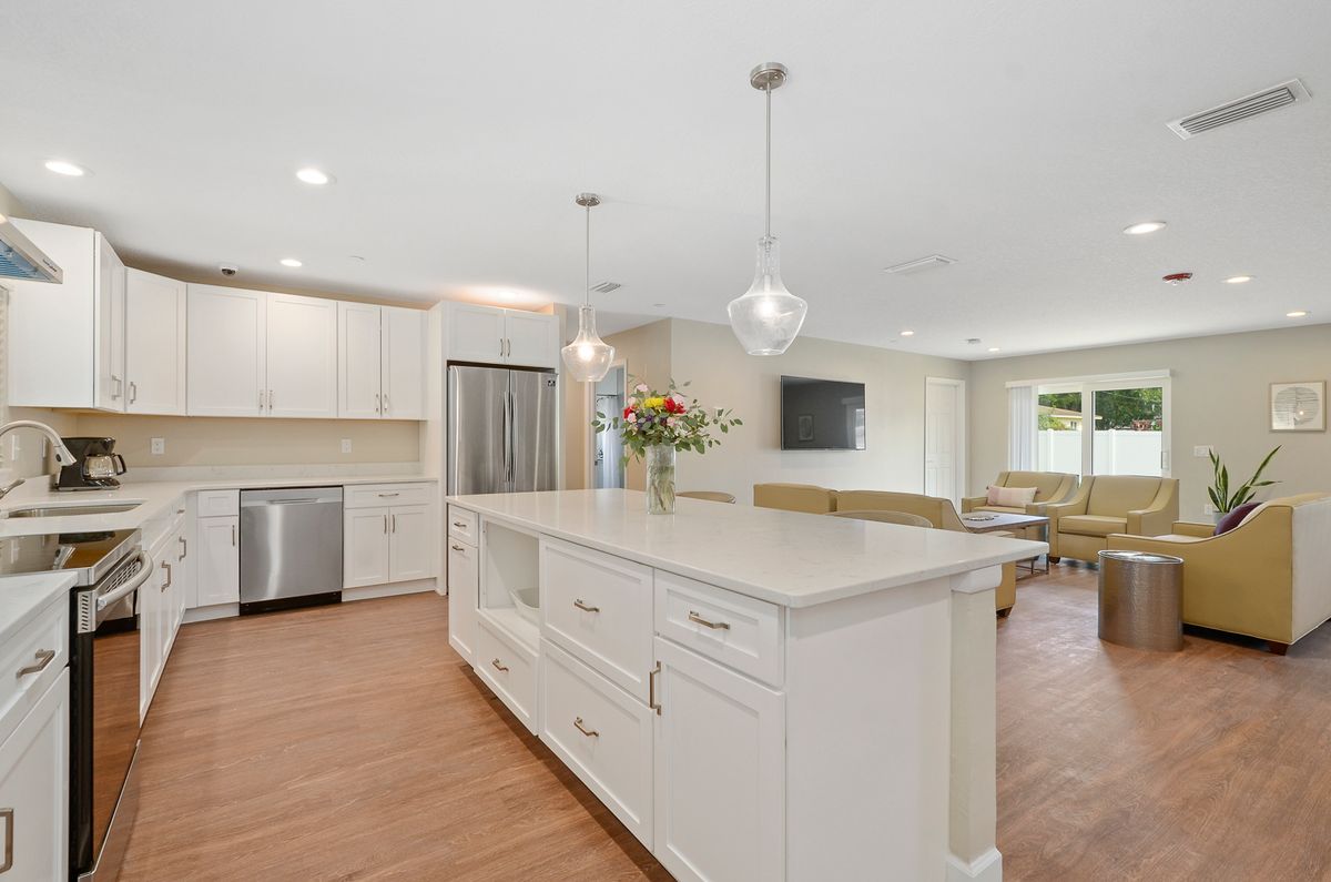 A modern kitchen featuring a large white island, stainless steel appliances, and pendant lighting.