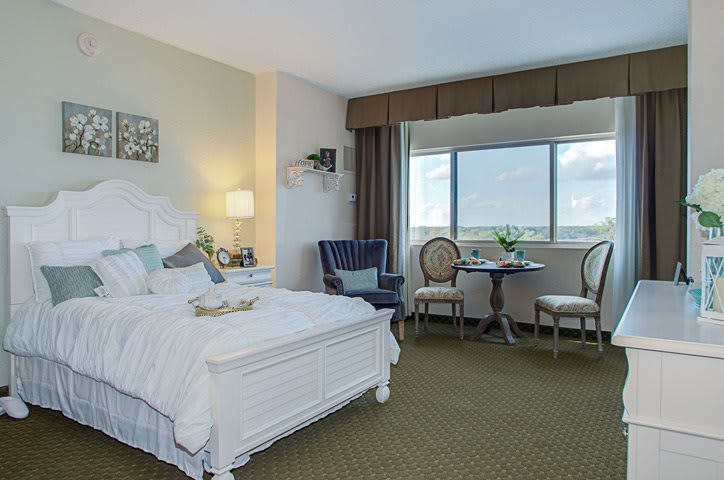 A well-decorated hotel room with a bed, seating area, and large window.