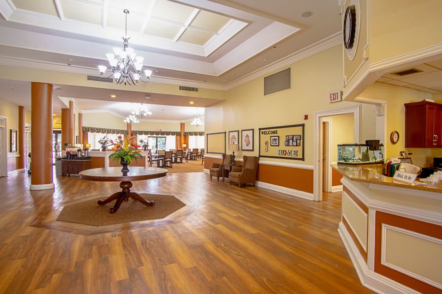 A spacious and elegantly designed lobby area with wood flooring, a chandelier, and comfortable seating.