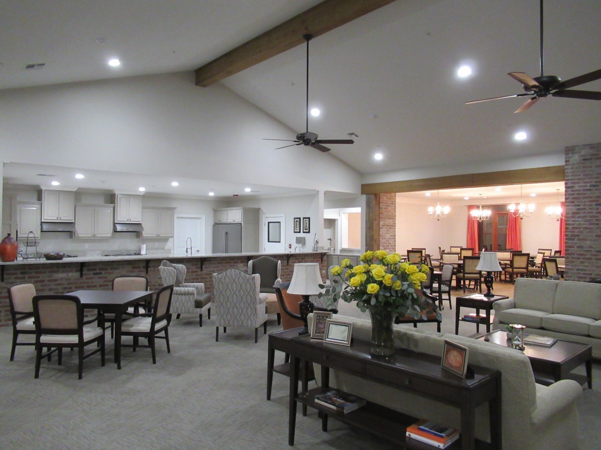 A spacious open-concept living area with a modern kitchen, dining tables, and comfortable seating.