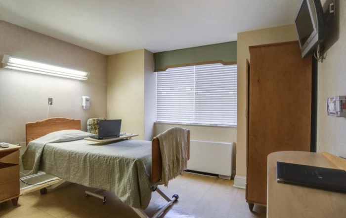 A well-lit hospital room with a single bed and a window.