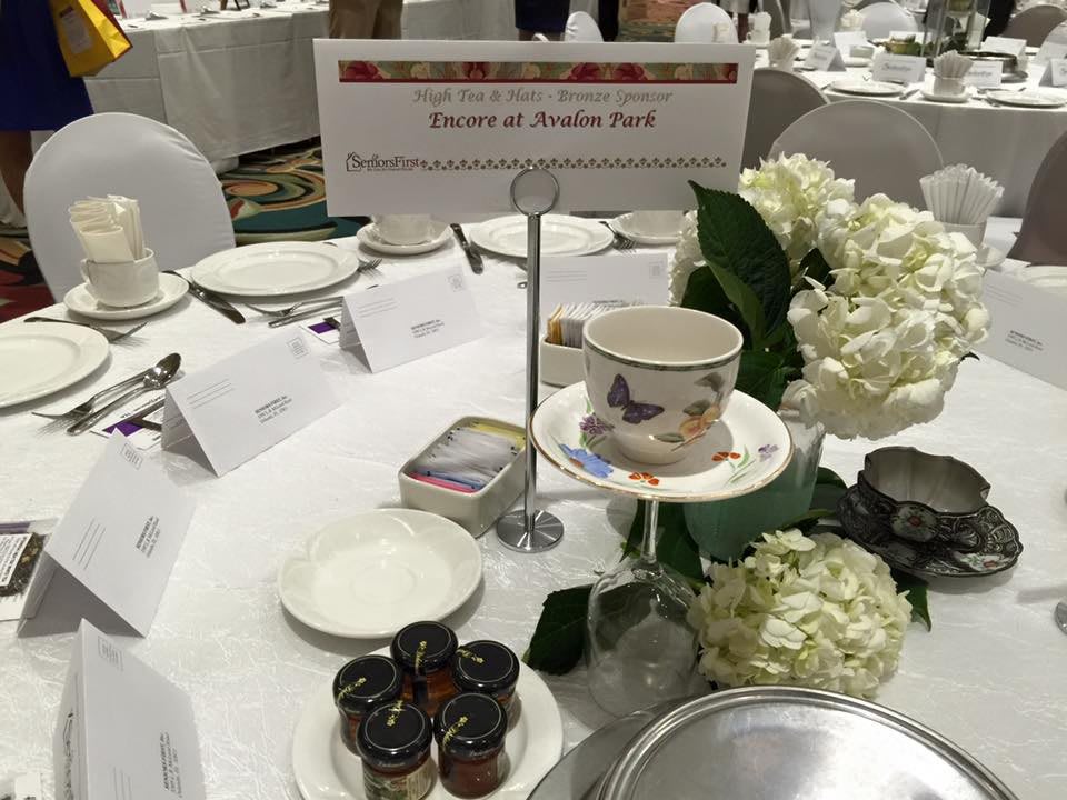 A beautifully set banquet table with place settings, name cards, floral arrangements, and small jars of jam.